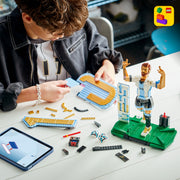 Child playing with LEGO soccer set on a table, with LEGO logo in corner.